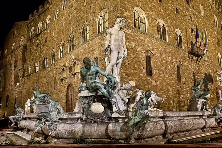 Fountain of Neptune at night in Piazza della Signoria, Florence, with Palazzo Vecchio behind