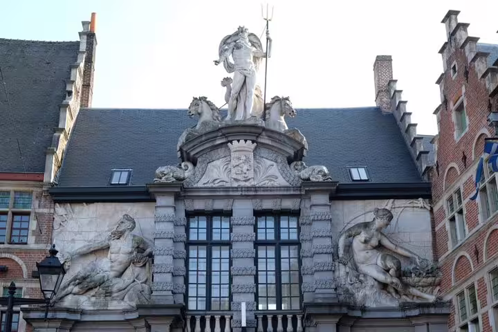 Baroque stone sculptures and Neptune statue on historic building facade in Ghent city center