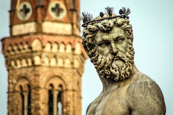 Close-up of Neptune statue with ornate crown, historic tower in background, Florence Italy