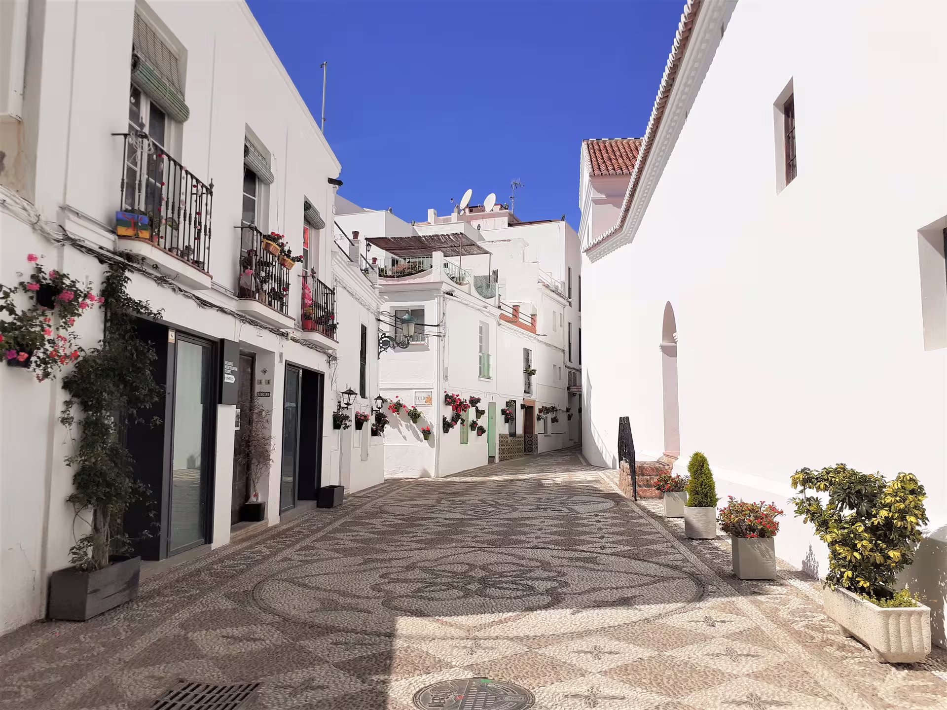 Whitewashed street in Nerja old town with flowered balconies, a highlight on a private day trip from Malaga