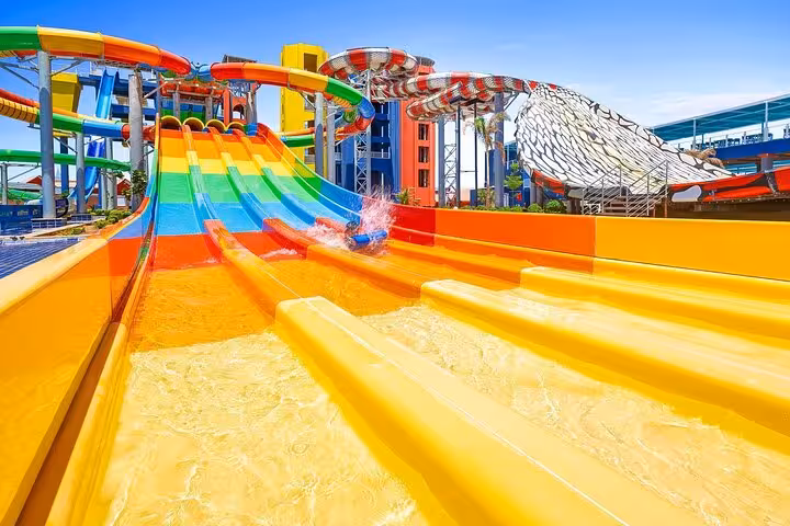Rider splashing down colorful multi-lane slide at Neverland Aqua Park Hurghada tour with lunch and transfers