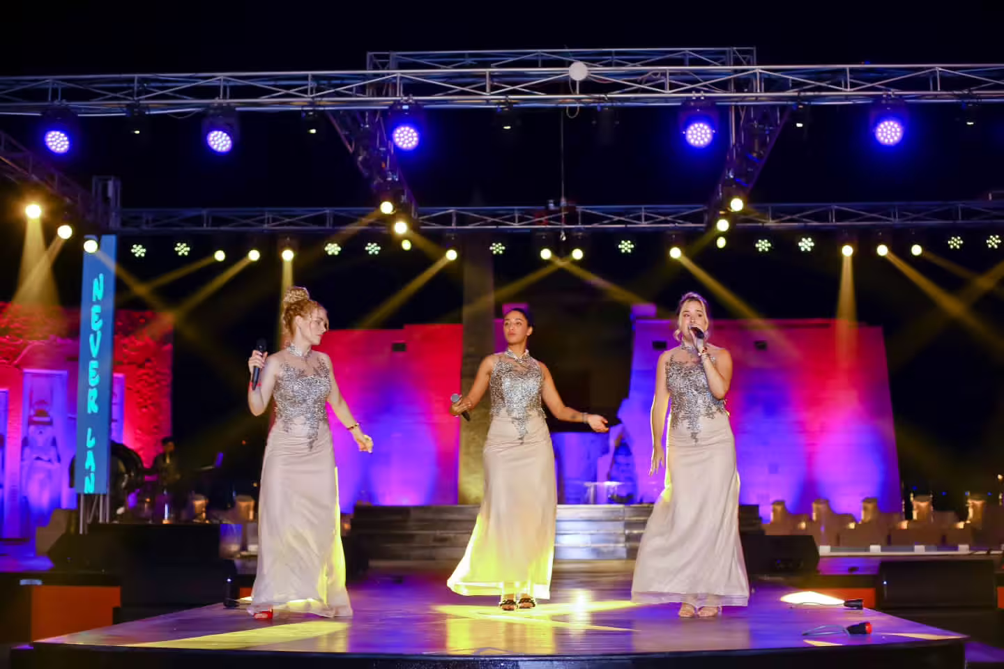 Three vocalists on stage at Neverland Show Sharm El Sheikh, sparkling dresses, live entertainment and lighting