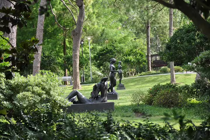 Bronze sculptures among lush green trees and manicured lawns in New Orleans City Park
