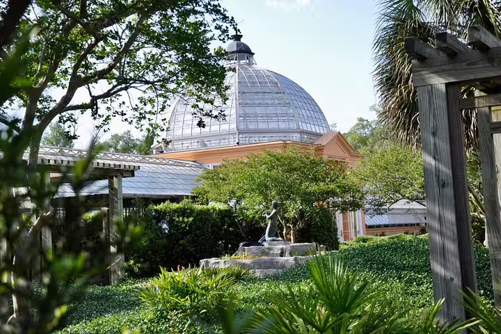 Glass dome greenhouse surrounded by lush gardens and trees in New Orleans City Park