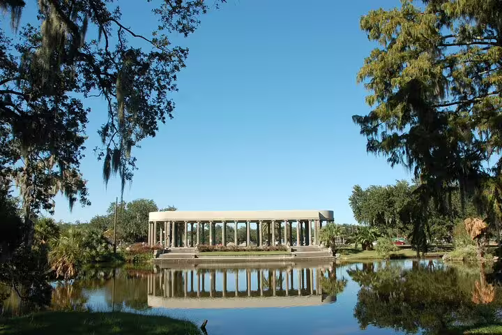 Peristyle pavilion reflected in lagoon at New Orleans City Park surrounded by Spanish moss trees
