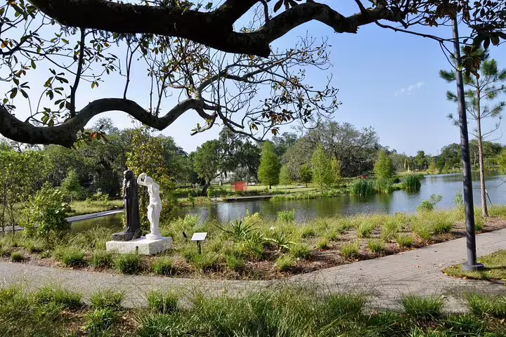 Sculptures and pond in New Orleans City Park with lush greenery and oak trees