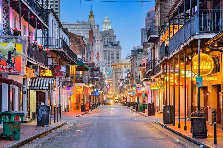 Bourbon Street in New Orleans French Quarter at dusk with neon signs and historic balconies