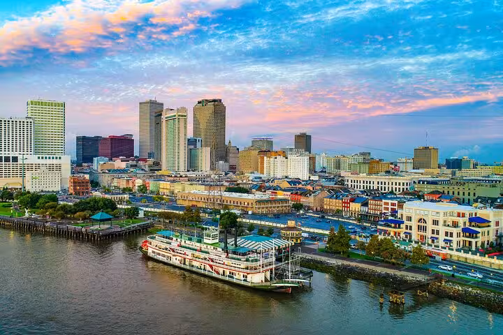 Aerial view of New Orleans French Quarter waterfront skyline with steamboat on the Mississippi River at sunset