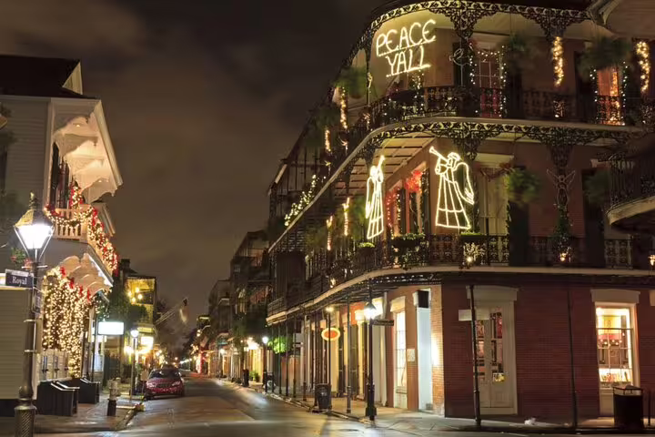 New Orleans French Quarter street at night with glowing holiday lights and ornate iron balconies