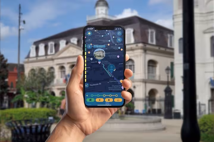 Hand holding smartphone displaying self-guided walking tour app map in New Orleans French Quarter