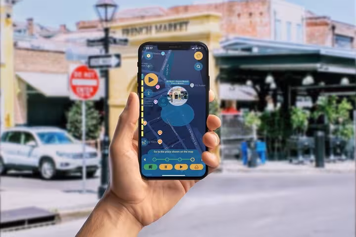 Hand holding smartphone with self-guided walking tour app map near New Orleans French Quarter French Market