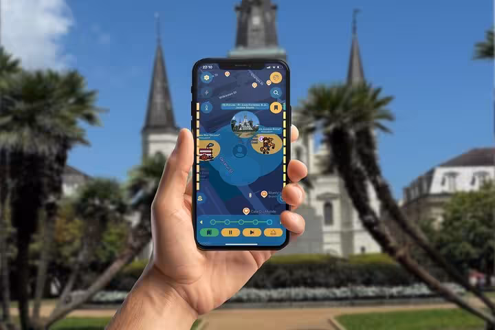 Hand holding smartphone with self-guided tour app in front of St. Louis Cathedral, New Orleans French Quarter