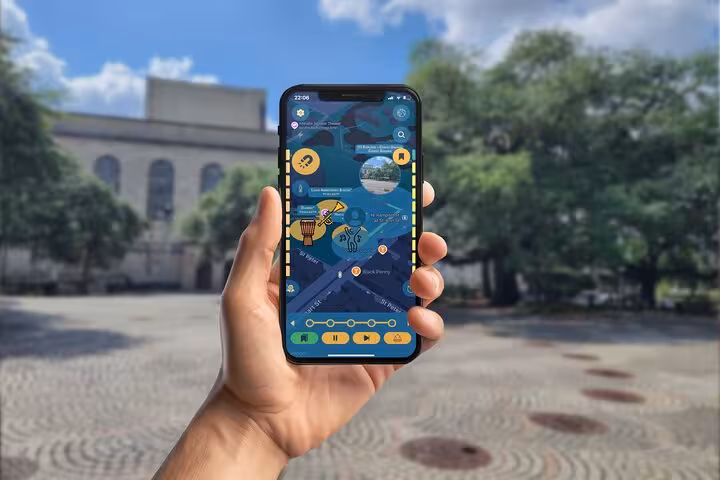 Hand holding smartphone displaying self-guided walking tour app map of New Orleans French Quarter