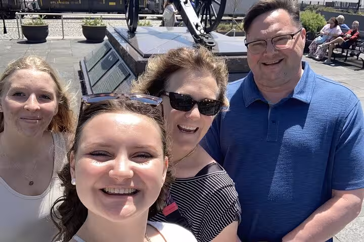 Group of four smiling tourists taking a selfie outdoors on a sunny day during a New Orleans walking tour
