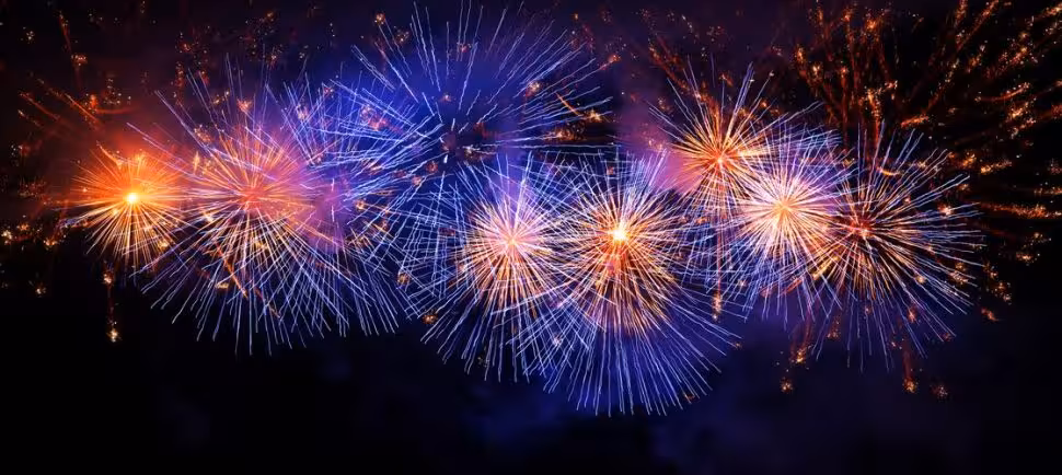 Colorful blue, purple and orange fireworks bursting against a dark night sky