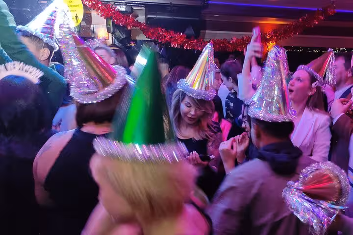 Crowded dance floor with party hats on New Year's Eve party cruise Istanbul, DJ music and festive lights