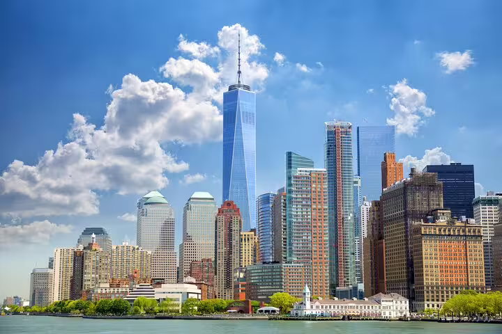 Lower Manhattan skyline with One World Trade Center towering over New York City waterfront on a sunny day