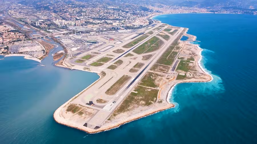 Aerial view of Nice Côte d'Azur Airport runway extending into the turquoise Mediterranean Sea