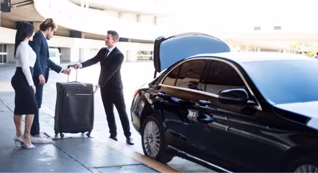 Chauffeur handling luggage next to black luxury sedan for private airport transfer on French Riviera