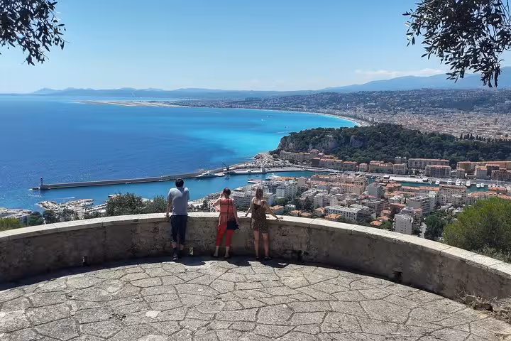 Tourists at Castle Hill viewpoint overlooking Nice harbor and turquoise French Riviera coastline