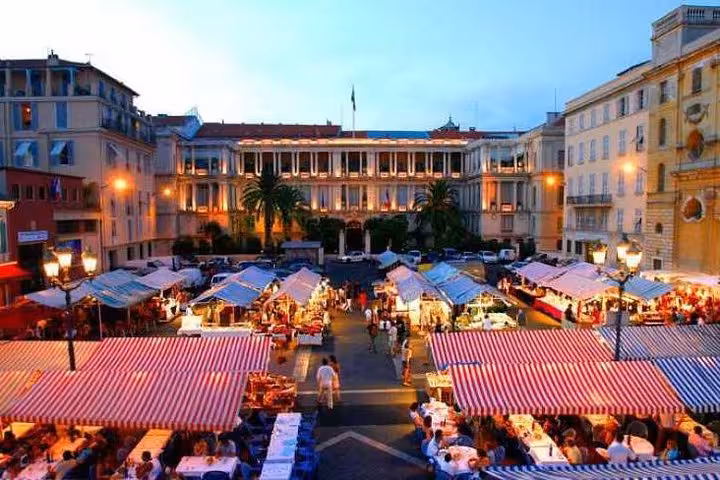Vibrant evening view of Nice's bustling outdoor market with colorful stalls and historic architecture.