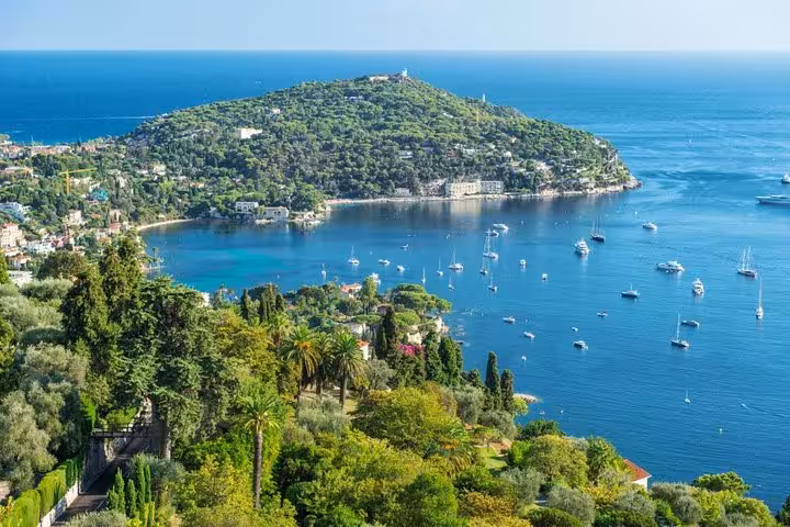 Aerial view of Villefranche-sur-Mer bay with sailboats and lush green peninsula near Nice, French Riviera