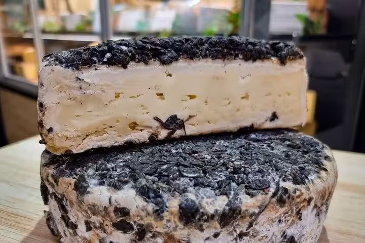Aged ash-coated cheese wheel cut open showing creamy interior, Nice gourmet food tour