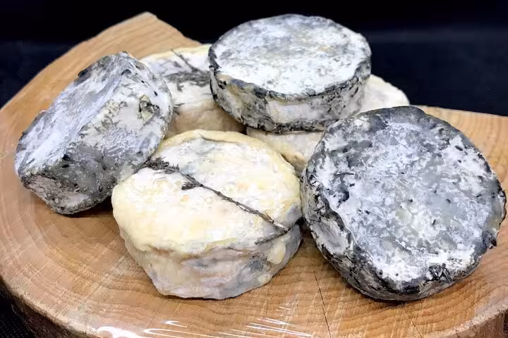 Aged French goat cheeses with mold-ripened rinds on a wooden board in Nice