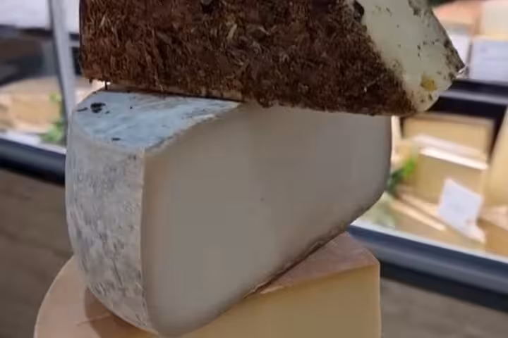 Stack of three artisan cheese varieties with different rinds at a Nice gourmet cheese shop