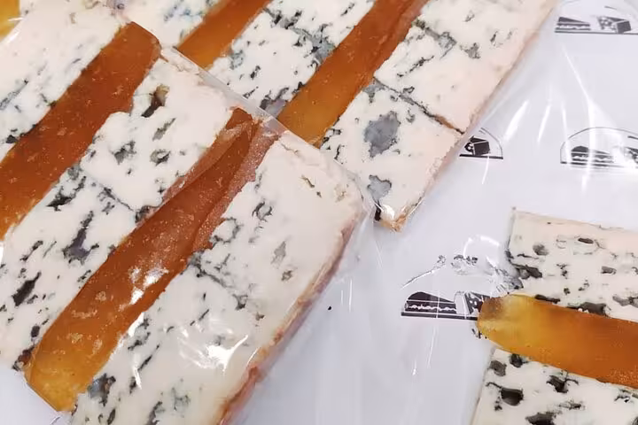 Slices of blue cheese paired with strips of quince paste on white paper in Nice