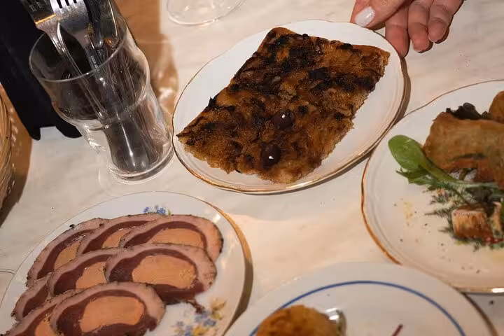 Sliced charcuterie and baked dessert with cherries on plates during Nice gourmet walking tour