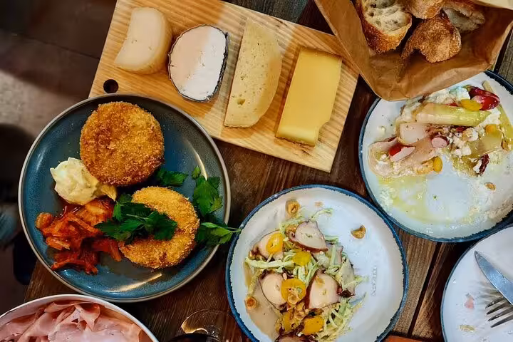 Cheese board, fried appetizers, octopus salad, and bread spread on a wooden table during a Nice gourmet tour