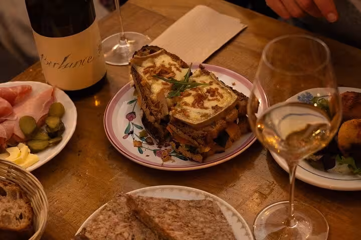 Croque monsieur sandwich with melted cheese and caramelized onions served on a floral plate with wine in Nice