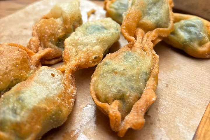 Golden fried dumplings with green filling on parchment paper during Nice gourmet walking tour