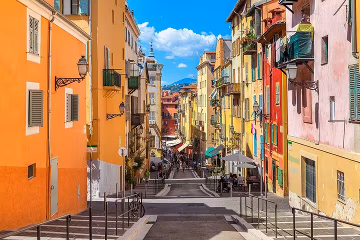 Colorful buildings lining a narrow sloped street in Nice Old Town on a sunny day