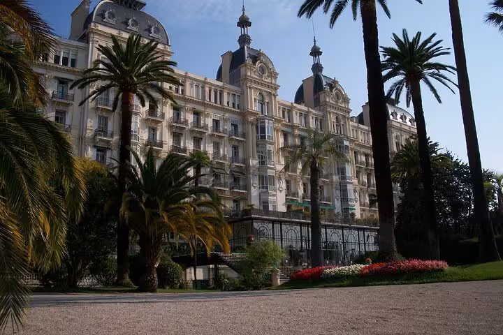 Grand Belle Époque hotel facade with palm trees and flower gardens in Nice, French Riviera