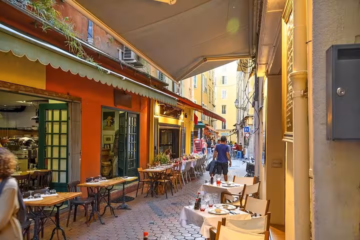 Colorful outdoor restaurant tables lining a narrow pedestrian alley in Nice Old Town