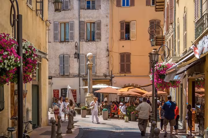 Charming pedestrian street with outdoor cafés, flower baskets, and historic buildings in Nice, French Riviera