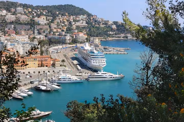 Aerial view of Nice Port with cruise ship and yachts in turquoise water, French Riviera hillside behind