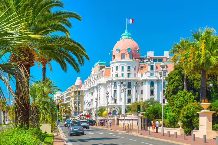 Hotel Negresco and palm-lined Promenade des Anglais in Nice, France under blue sky
