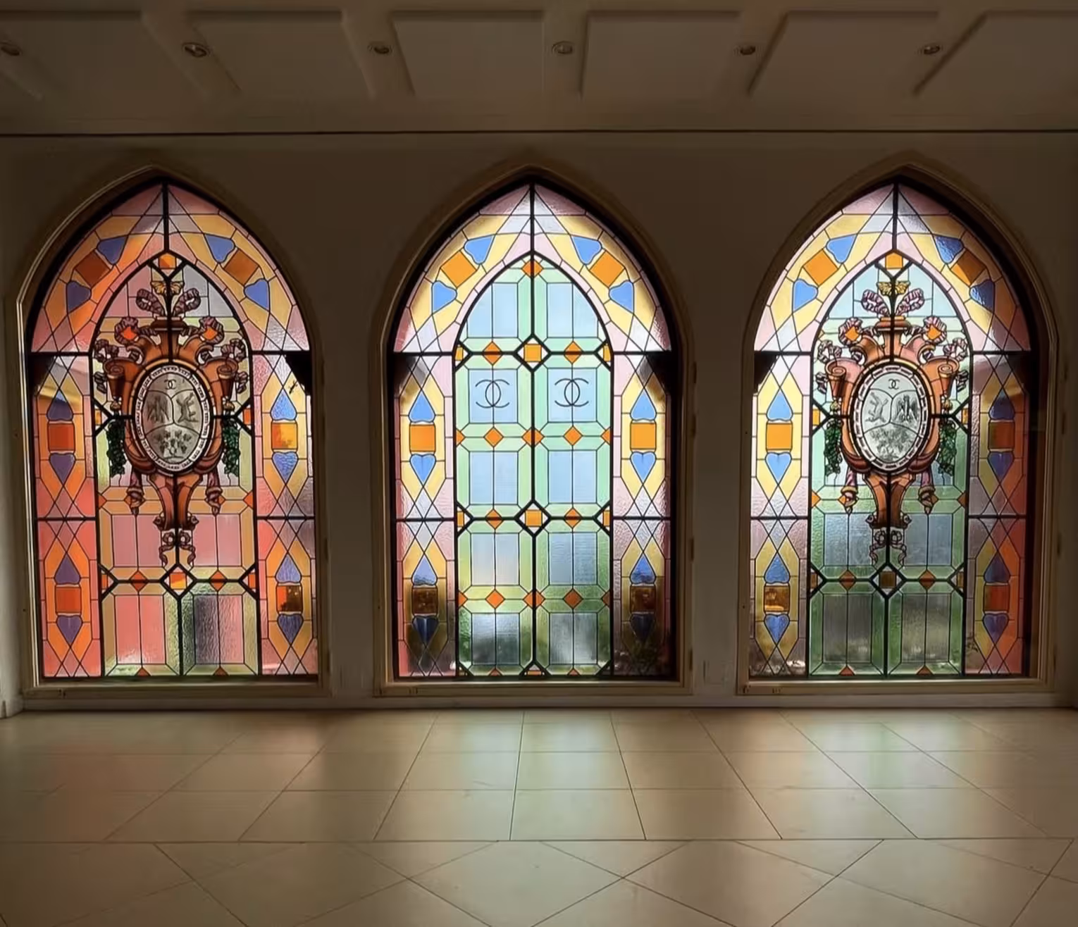 Colorful Gothic stained glass windows with heraldic crests at a historic French vineyard