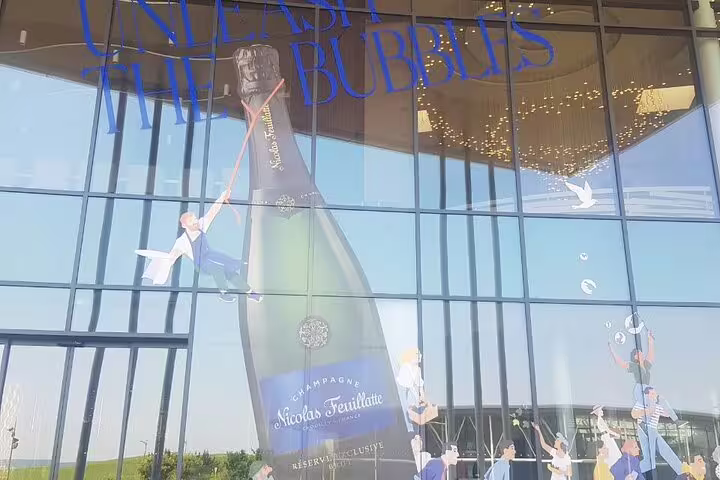 Giant Nicolas Feuillatte champagne bottle display on Reims winery facade, part of Champagne and Reims day trip from Paris