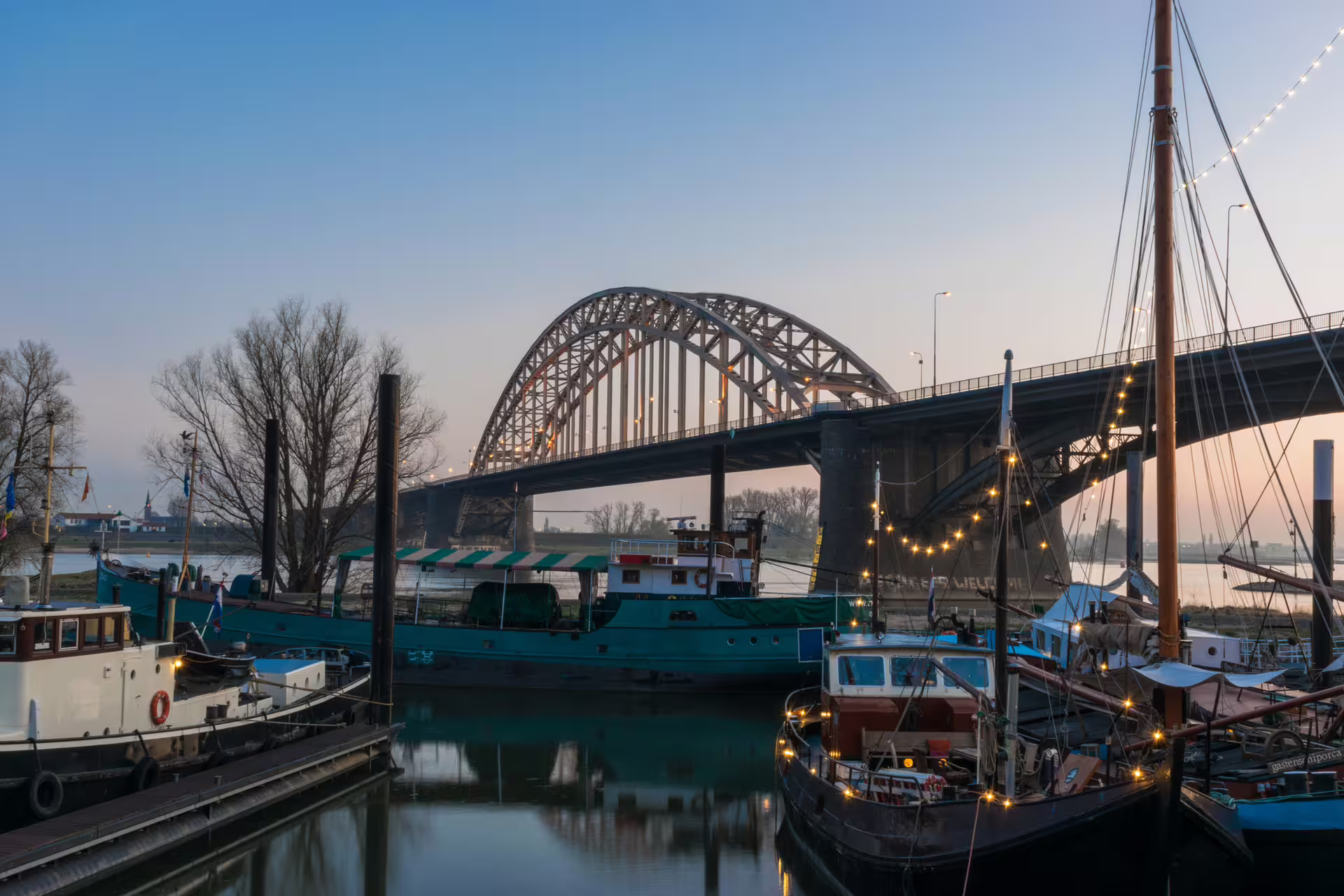 Waalbrug bridge and boats at dusk in Nijmegen, scenic stop on 1-day walking tour with audioguide in 7 languages