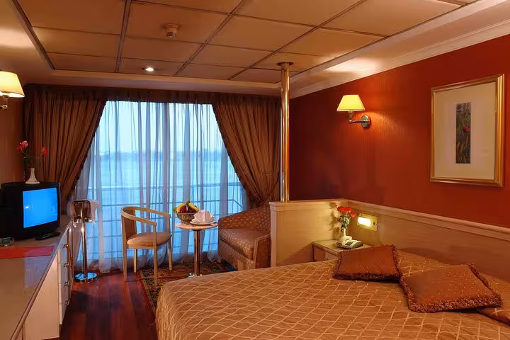 Nile cruise cabin with balcony river view, double bed and lounge seating on Luxor to Aswan 5-day tour