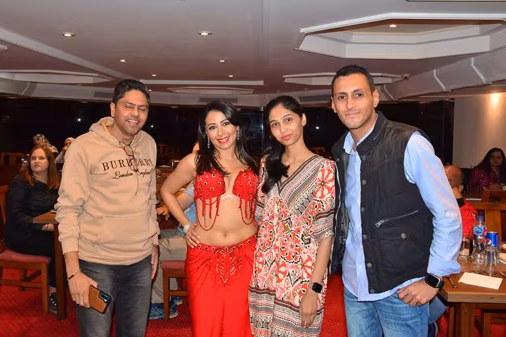 Guests pose with a belly dancer during a lively Nile cruise dinner with live entertainment.