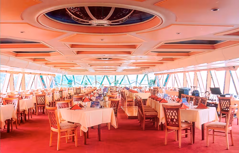 Elegant Nile dinner cruise dining hall in Cairo with set tables, panoramic windows, and red carpet seating