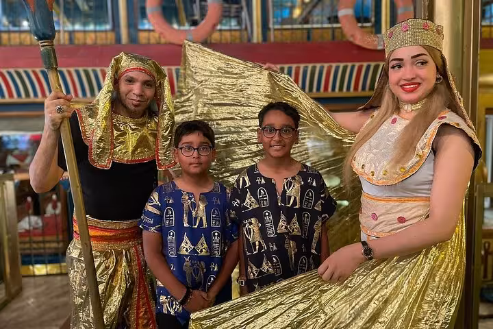 Guests pose with Egyptian performers in pharaonic costumes on a Nile River dinner cruise with live music