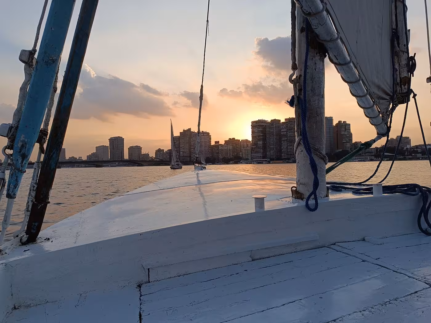 Sunset view from a Nile felucca in Cairo with city skyline, relaxing sailing tour with lunch and hotel transfer