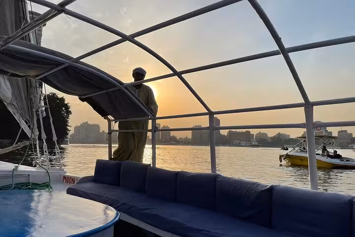 Sunset view from a Nile felucca deck in Cairo with cushioned seating and river skyline on a sailing tour