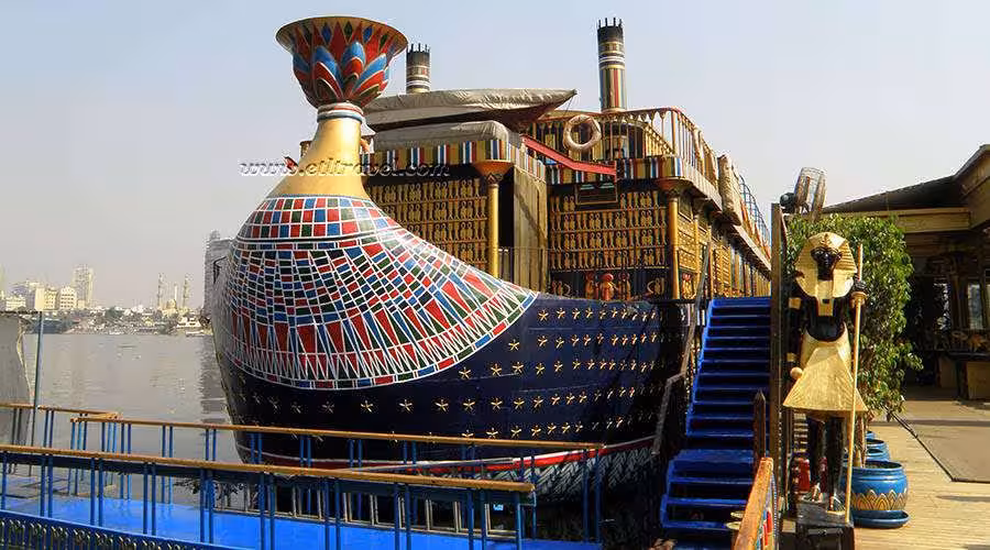 Pharaoh-style Nile cruise ship docked on the river, colorful Egyptian decor for Nile Pharaohs Cruising Booking